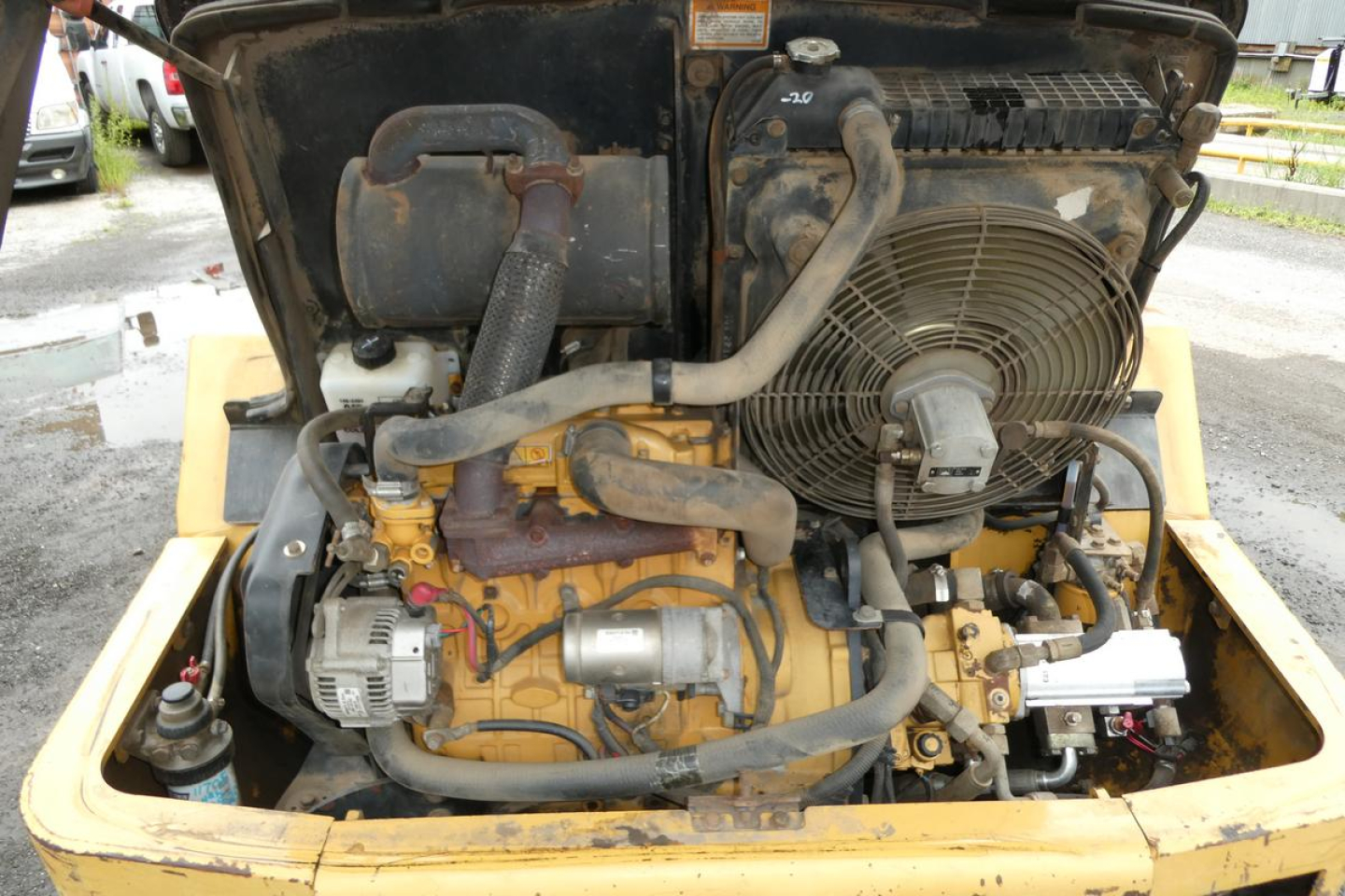 Caterpillar 902 engine bay showing radiator, hoses, belts, and exposed engine components.