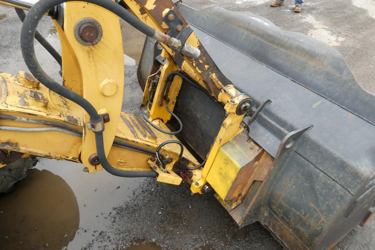Caterpillar 902 compact wheel loader arm and bucket linkage with hydraulic cylinders and hoses visible.