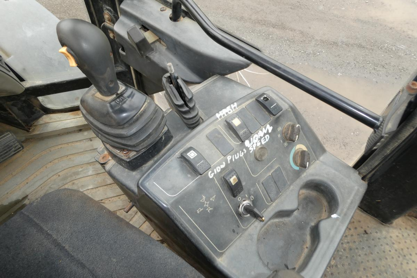 Caterpillar 902 wheel loader cab interior showing joystick controls and dashboard with switches and levers.