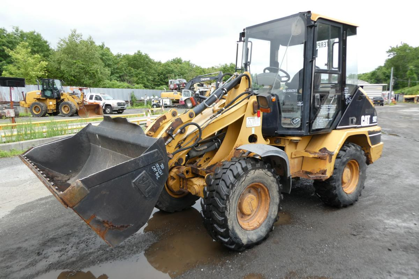 Wheel loader in_service showing front bucket and CAT hydraulic arms with enclosed cab, Caterpillar 902 model, used condition.