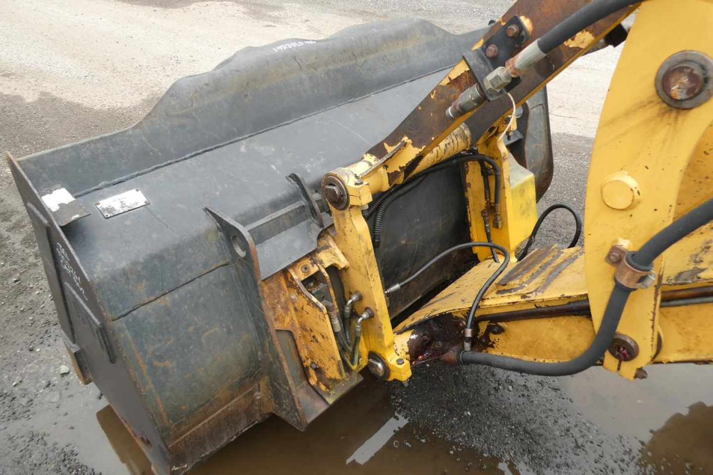 Caterpillar 902 wheel loader attachment showing hydraulic coupler and yellow arm with dark gray bucket hinge area.