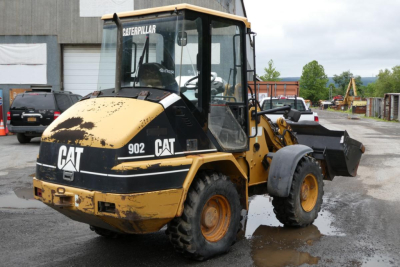 Wheel loader showing Caterpillar 902 compact loader with yellow and black paint, front bucket, CAT branding, and worn exterior.
