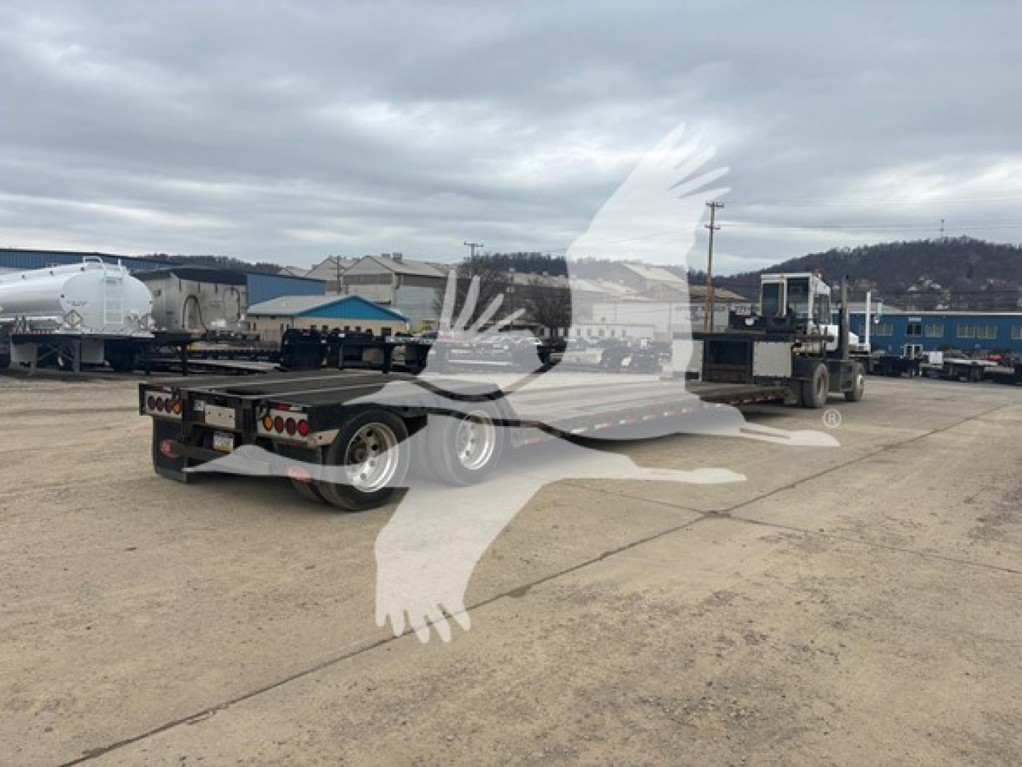 Trailer with low profile double drop expandable feature in a yard; visible text includes VIN 4U3J048247L007257 and stock PC-8717 on a trailer in the background.