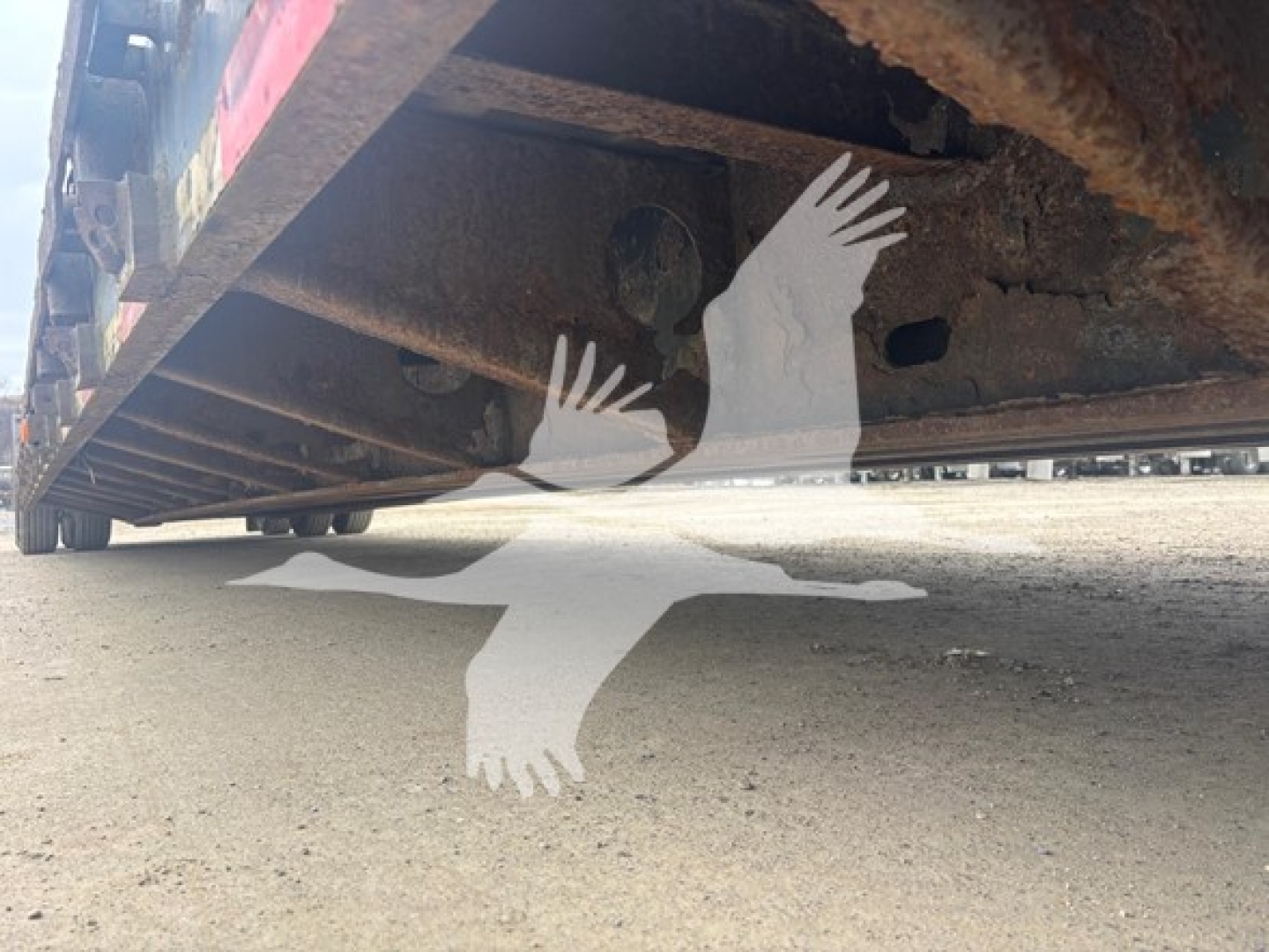 Trailer underside view with rusted frame and ground clearance; appears to be a double drop expandable trailer.