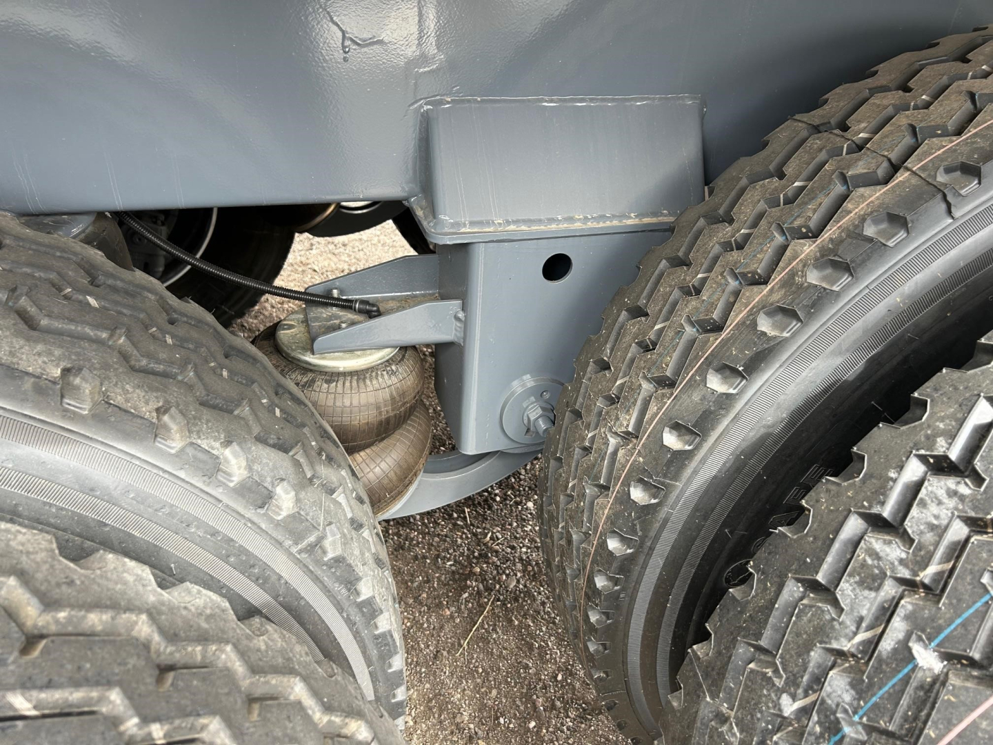 Trailer underside showing suspension components and dual rear tires on a new vacuum tank trailer.