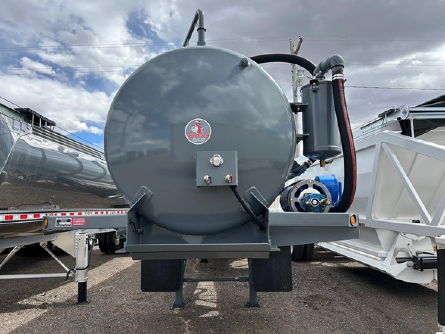 Tank-style air ride trailer rear view with circular pressure tank, hydraulic lines, and pump assembly mounted on a tri-axle chassis.
