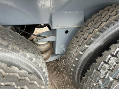 Trailer underside showing suspension components and dual rear tires on a new vacuum tank trailer.