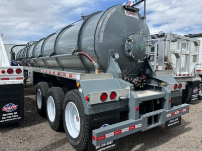 Trailer rear view showing a tri-axle air ride vacuum tanker with gray cylindrical tank and rear bumper guards.