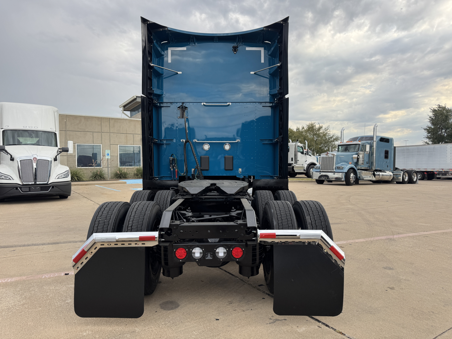 Kenworth T680 rear view showing fifth wheel and dual rear axles with mud flaps and bumper lights.