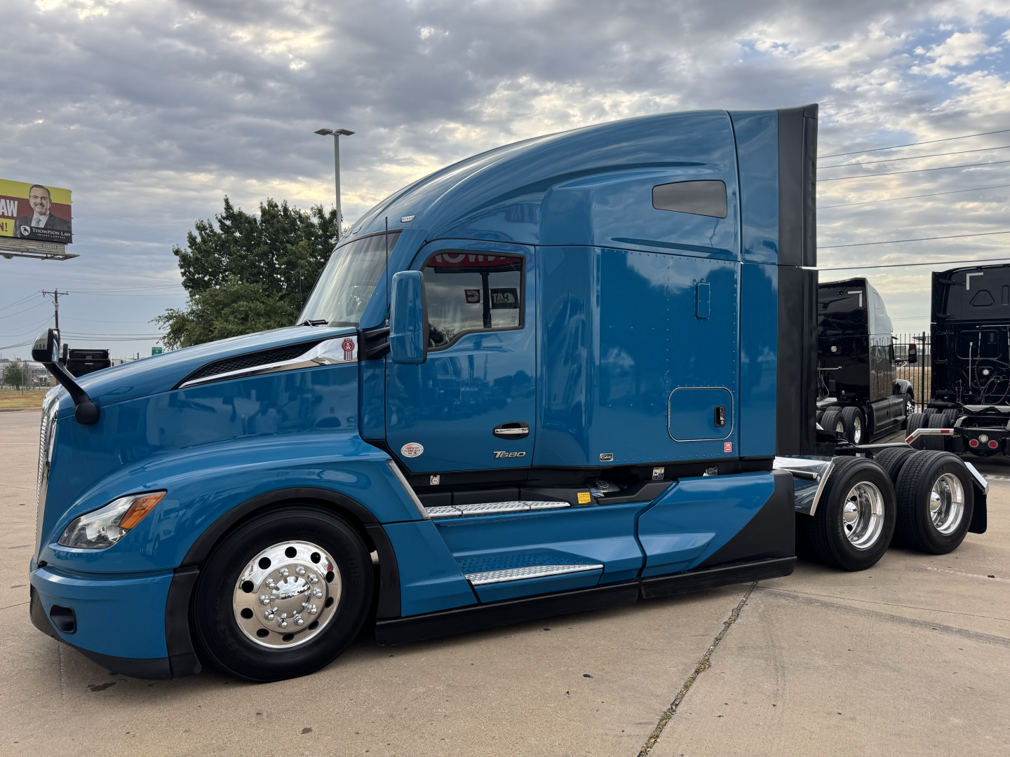 Kenworth T680 tractor trailer in blue side view showing cab and front wheel area.