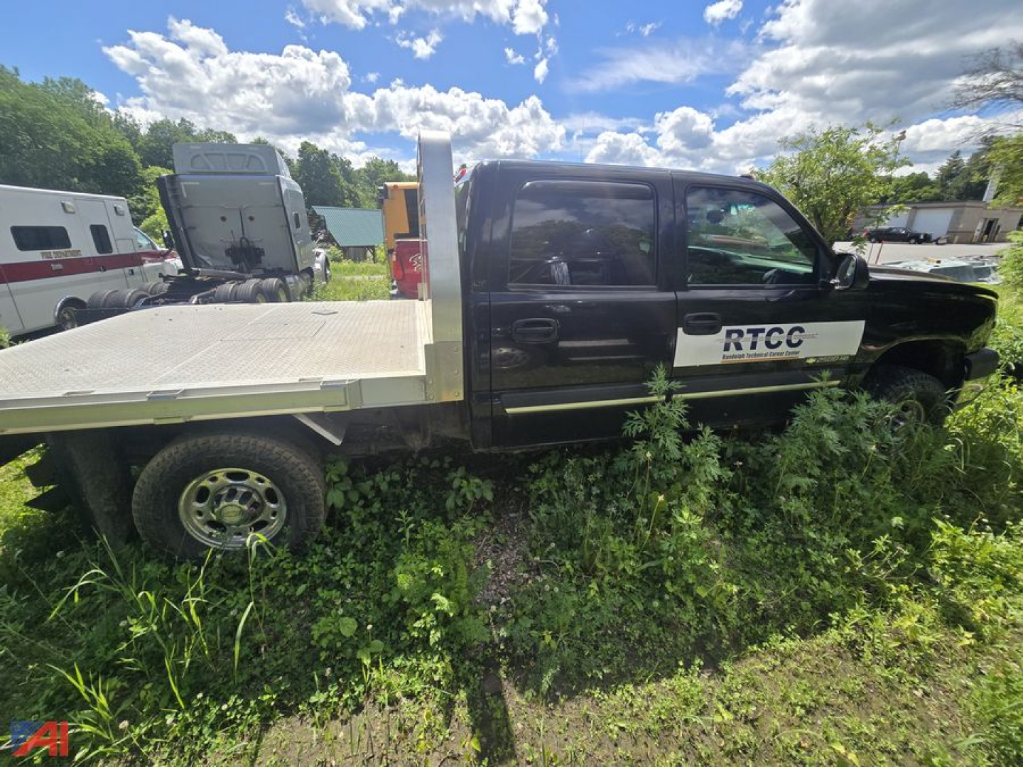 2005 Chevrolet Silverado 2500HD Crew Cab flatbed truck with RTCC logo on door, shown in grassy lot with blue sky