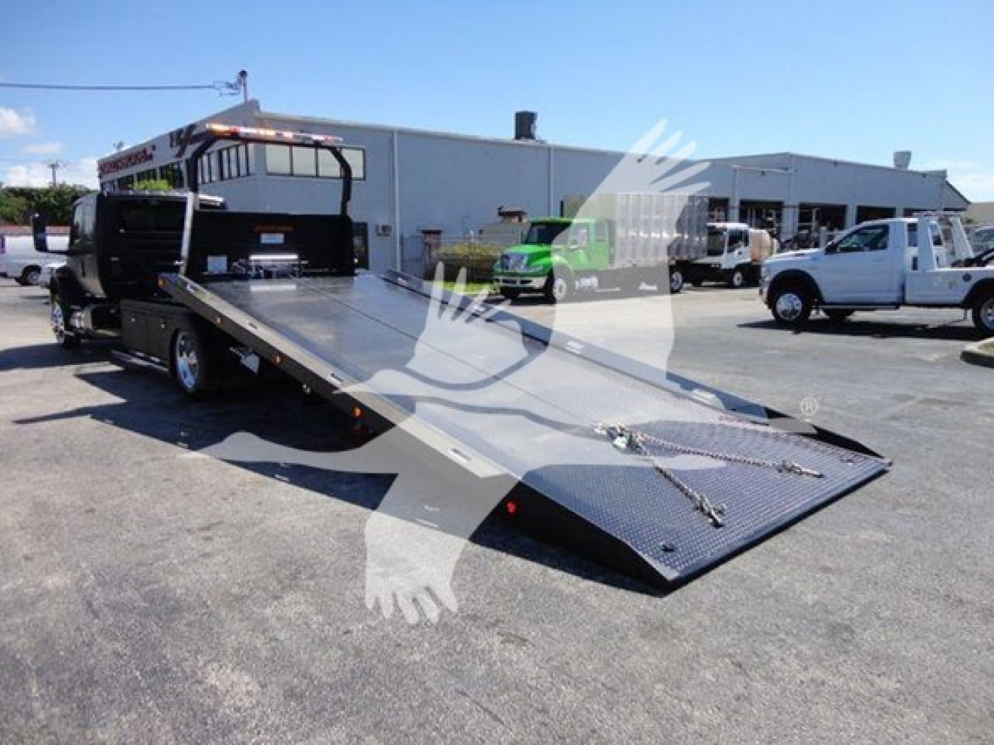 MV 2022 International rollback truck with flatbed tow bed and loading ramp shown in an outdoor lot.
