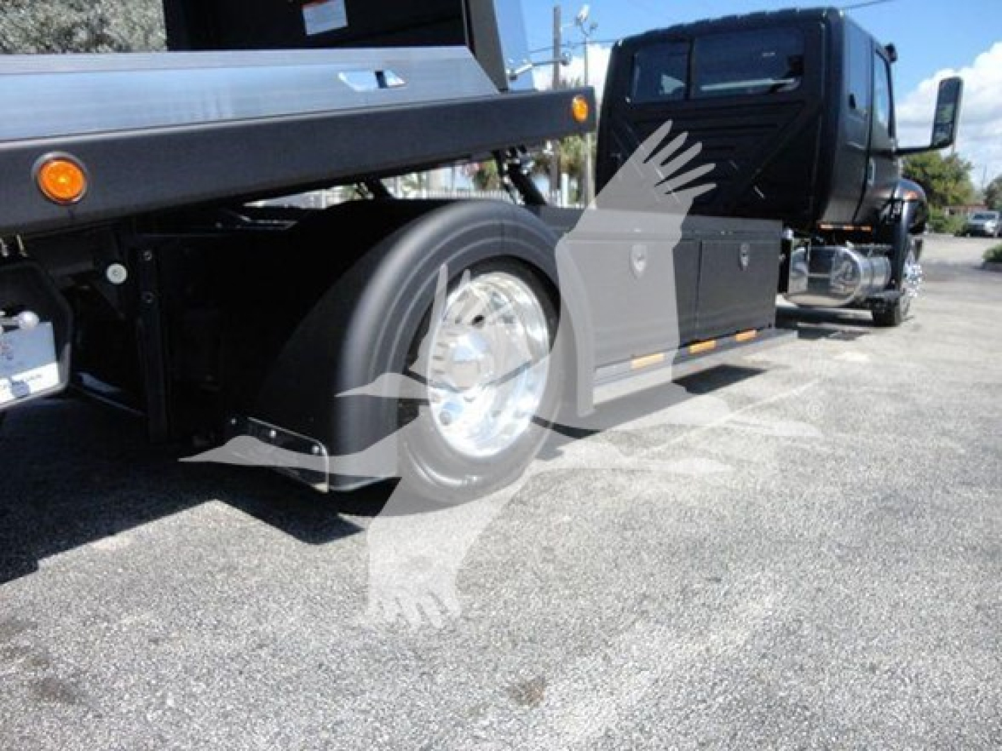 Truck chassis and wheel area of a 2022 International MV rollback truck, with side toolboxes and rear wheel visible.