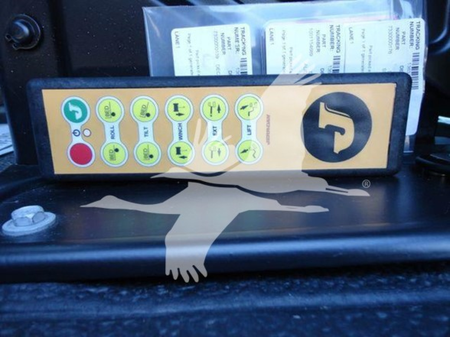 Control panel with green circular icons and a large yellow control module inside a truck's interior; small labels and papers behind.