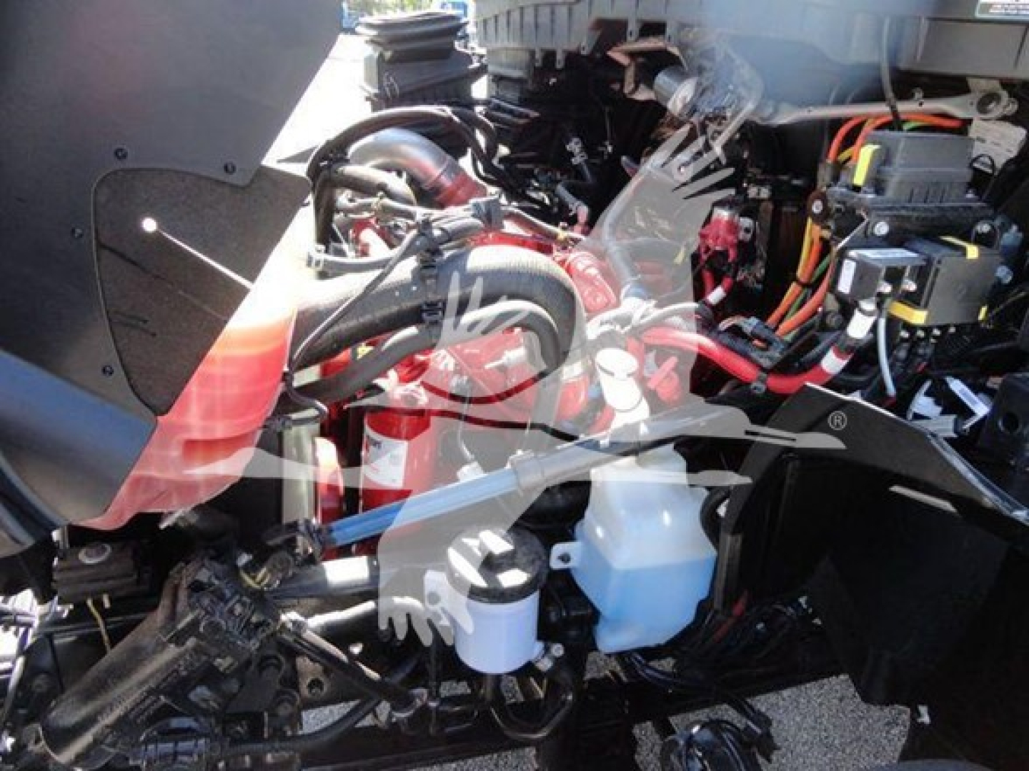 Truck engine bay showing coolant reservoir, hoses, and wiring in a 2022 International MV rollback truck.