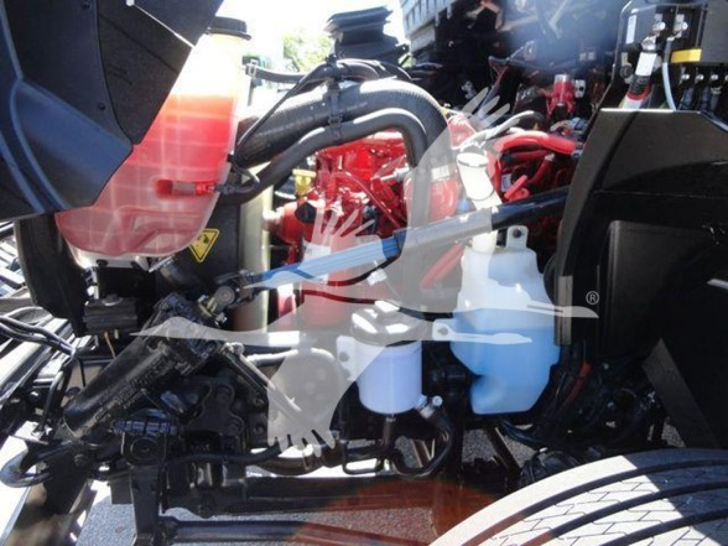 Trucks engine bay with red engine components, coolant reservoir, and hoses visible.