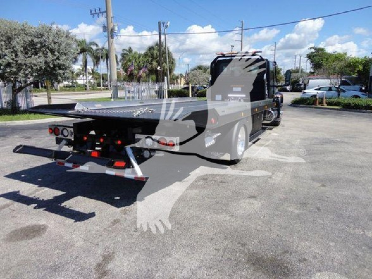 Tow truck bed and cab of a flatbed rollback tow truck; visible text on side panels and rear includes generic branding but no legible model numbers.