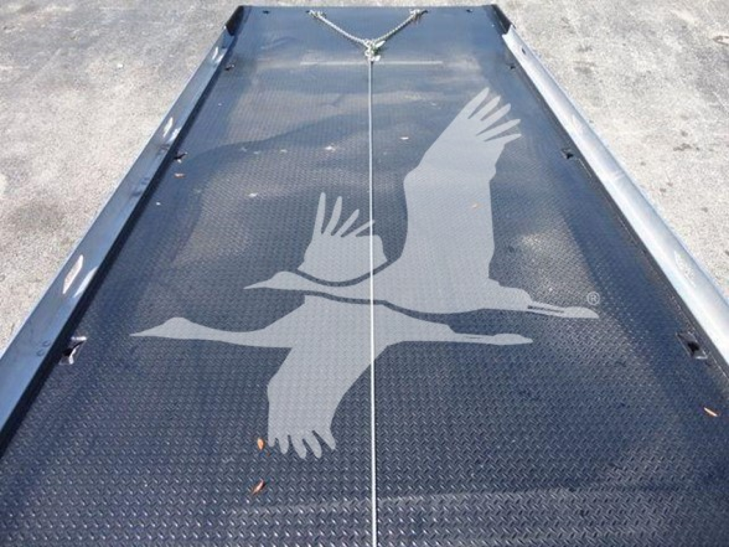 Flatbed or loading ramp with diamond plate surface showing a large graphic of two birds in flight.