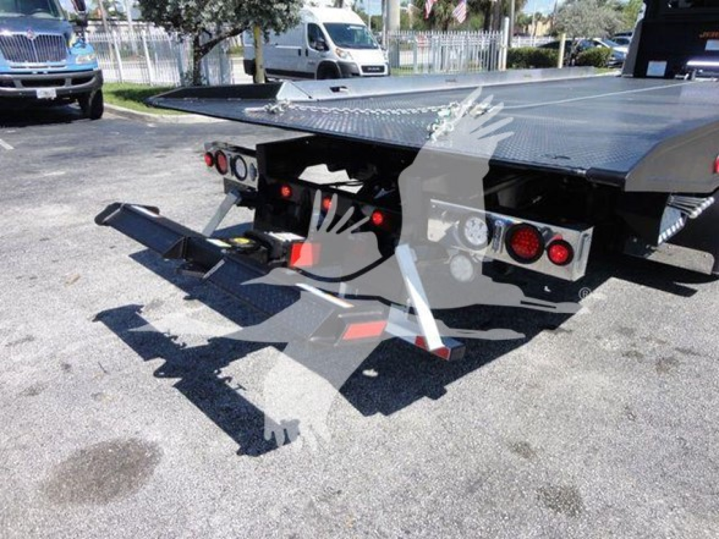 Truck rollback bed with hydraulic ramps and dual taillights, back view showing platform and towing apparatus.