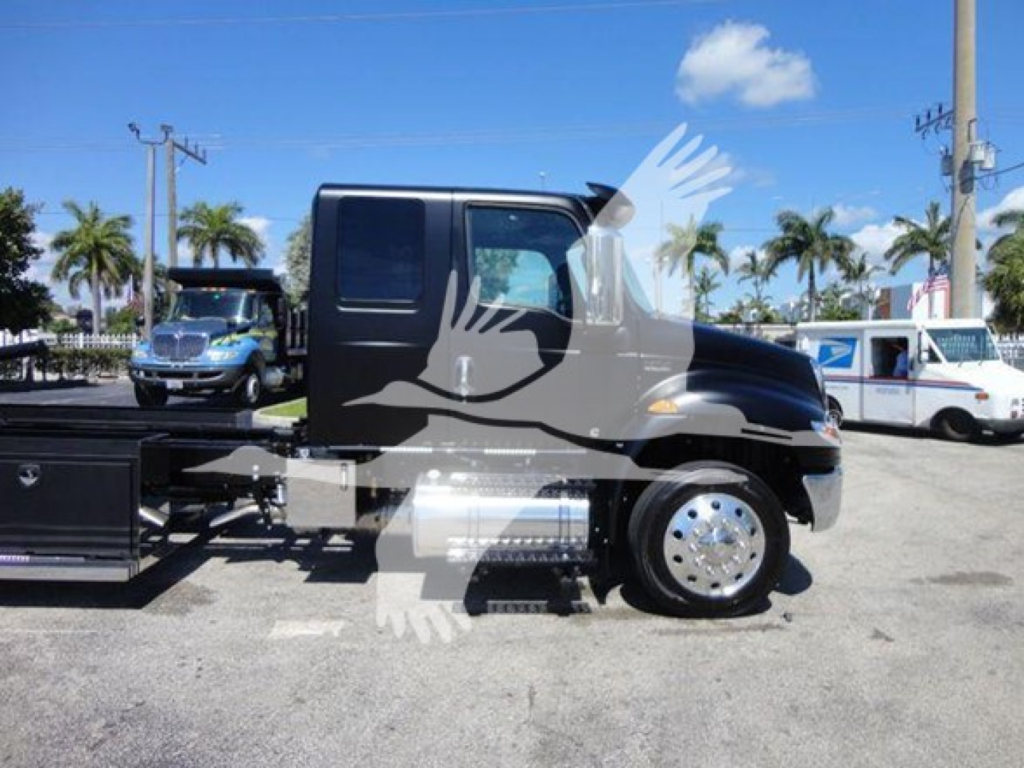 Truck side view showing 2022 International MV rollback truck cab with black exterior, wheel, and chrome hubcap.