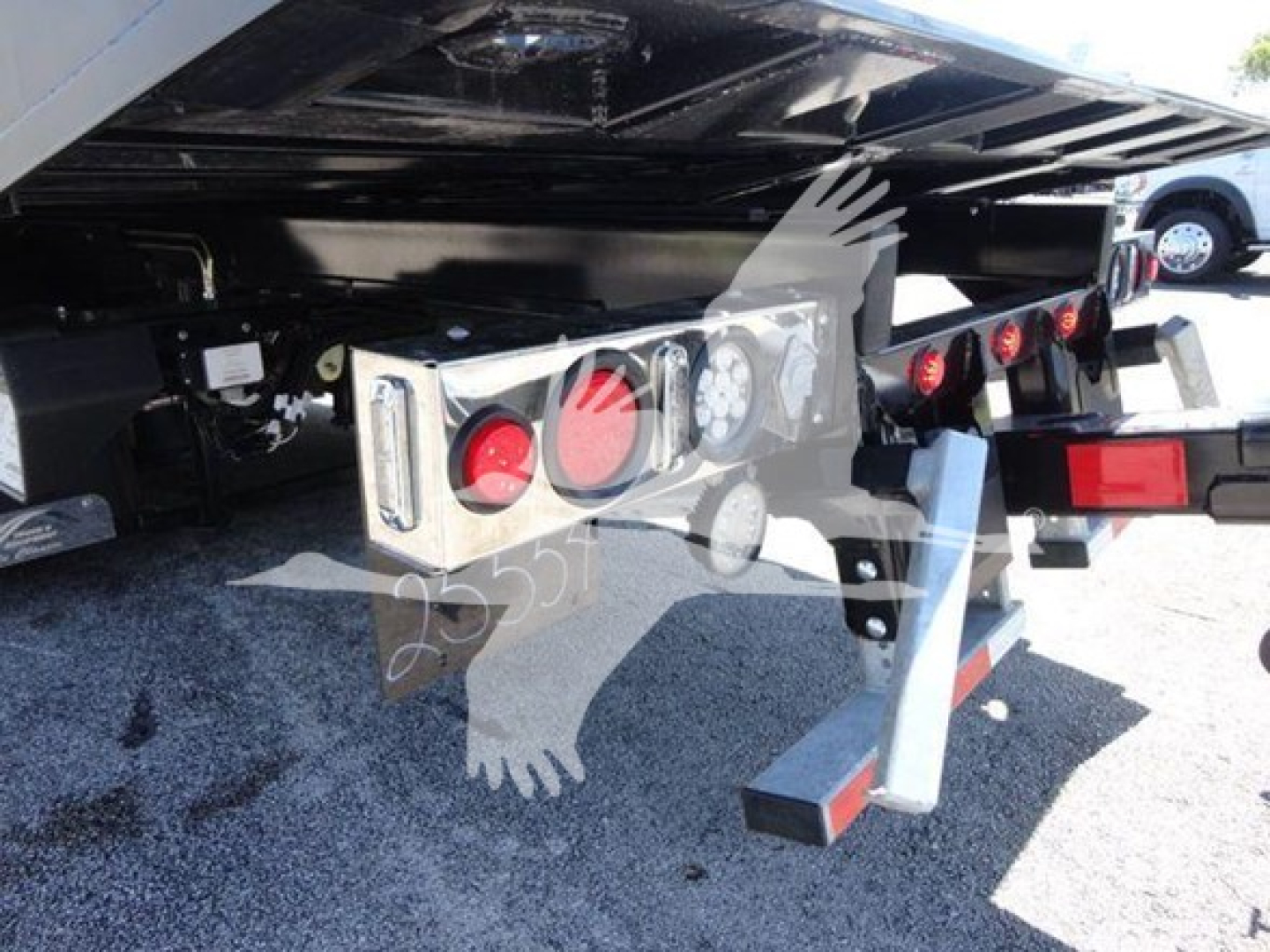 Trailer hitch area of 2022 International MV rollback truck showing rear lights, bumper, and support structure with hydraulic lines and wiring; license plate area not visible.