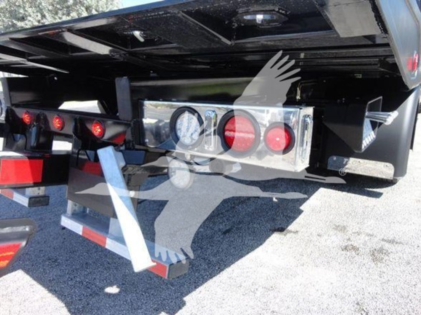 Trailer rear showing taillight panel and bumper with safety chains and metal brackets.