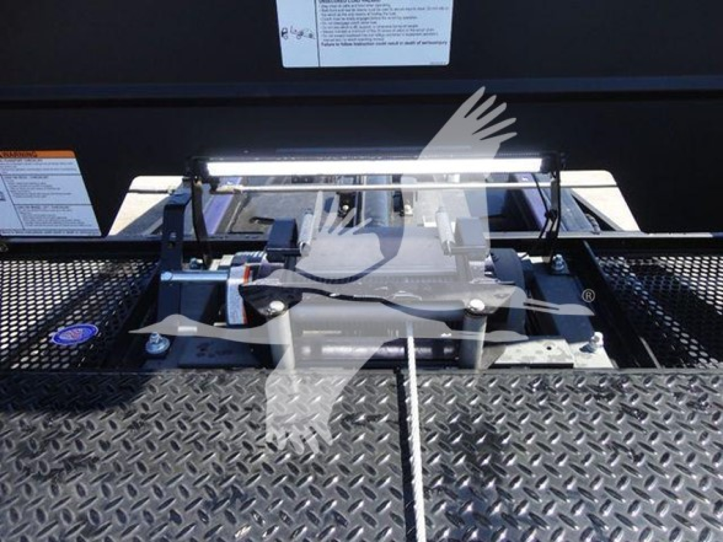 Trucks equipment mounting hardware on diamond plate surface with a bright LED strip and hydraulic/metal components in view.