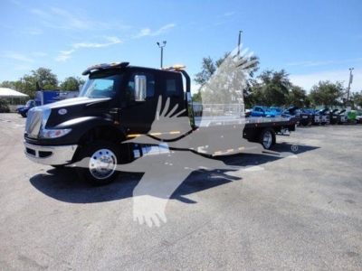 Flatbed tow truck in a dealer lot with a partial watermark, showing International MV cab and flatbed.