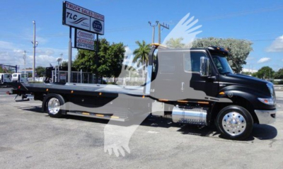 International MV tow truck flatbed with black cab and gray chassis showing side profile and chrome fuel tanks.