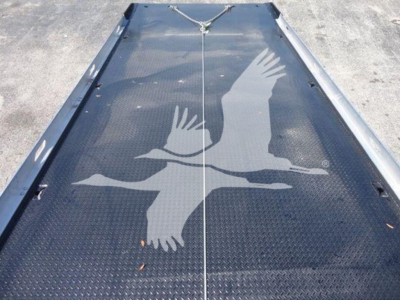 Flatbed or loading ramp with diamond plate surface showing a large graphic of two birds in flight.