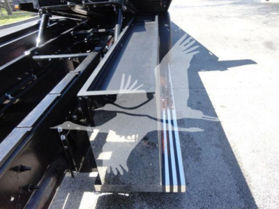 Truck rollback body with steel steps and hydraulic machinery visible in the bed area; metallic rails and support brackets present.