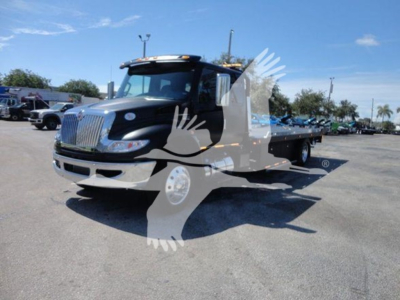 Truck in a dealership lot with a black cab and flatbed, logo watermark across image, visible text on truck area not legible.