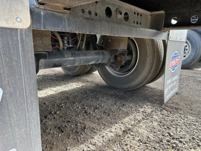 Flatbed trailer undercarriage with rear tire, suspension, and ULF brand mudflap showing 2024 Wabash Air Ride Steel Flatbed components.