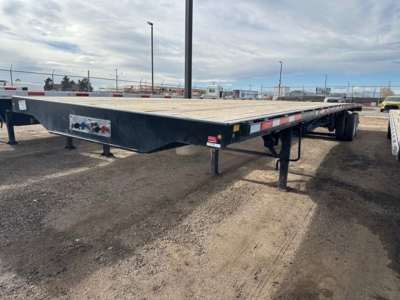 Wabash Apiton flatbed trailer showing deck, dual axles, landing legs, and rear lights.