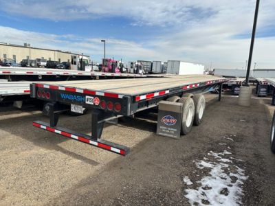 Flatbed trailer by Wabash with stock number 1516, rear view showing taillights and bumper, in a dealership lot.