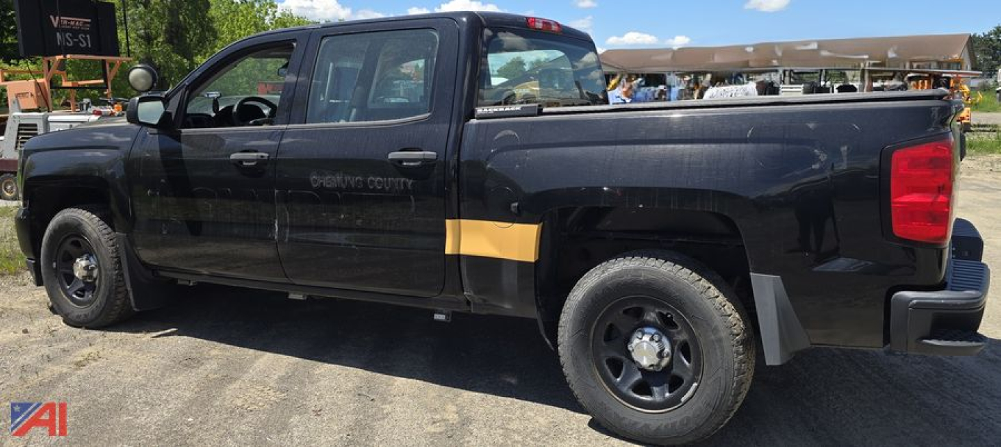 Chevrolet Silverado 1500 crew cab police edition pickup truck side view with dark paint, yellow police stripe, and black wheels.
