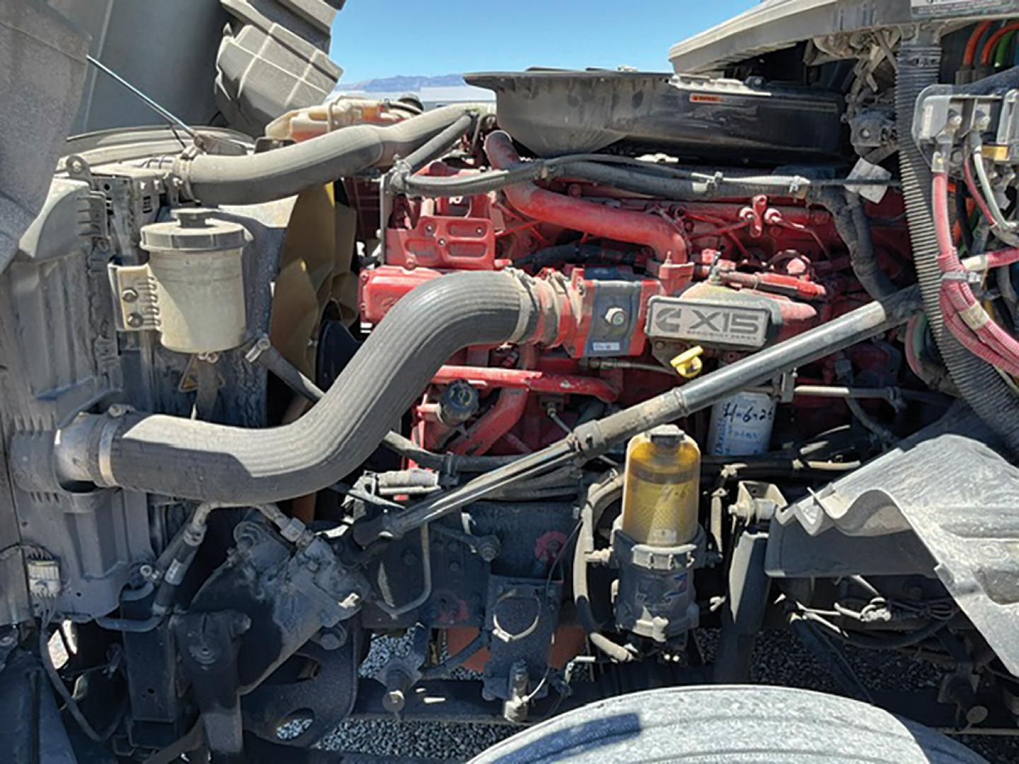 Engine bay of a 2019 International LT625 showing red engine components, hoses, and air intake; visible labels and fluid reservoirs.