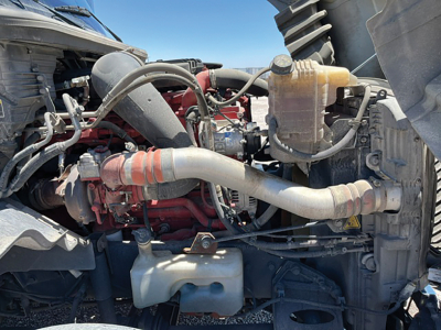 Truck engine bay showing International LT625 diesel engine with red engine block, multiple hoses, and coolant reservoir.