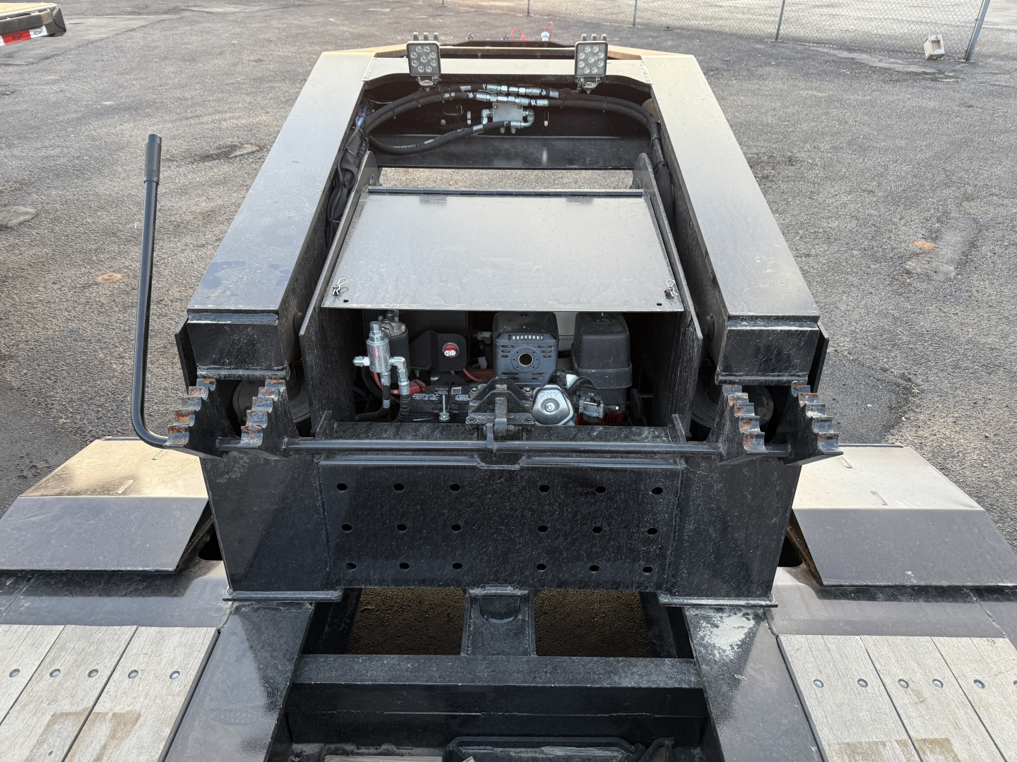 Trailer undercarriage showing hydraulic system and mounting area with engine compartment and metal ramps.