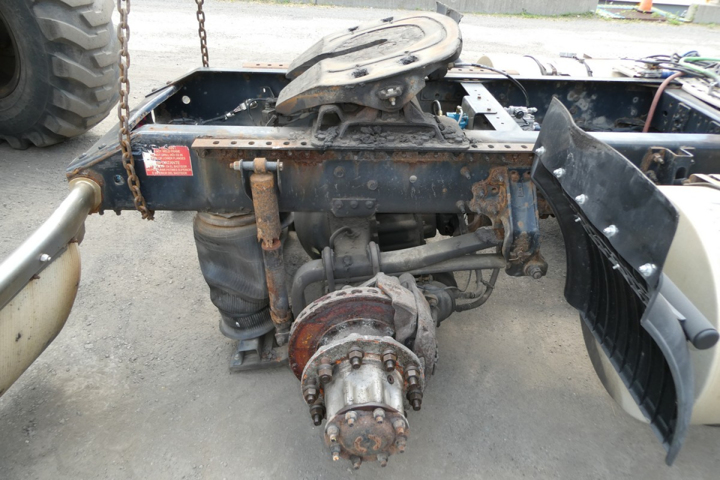 Rear view of a Volvo truck chassis showing drivetrain and differential assembly undercarriage with mounted components and chain in view.