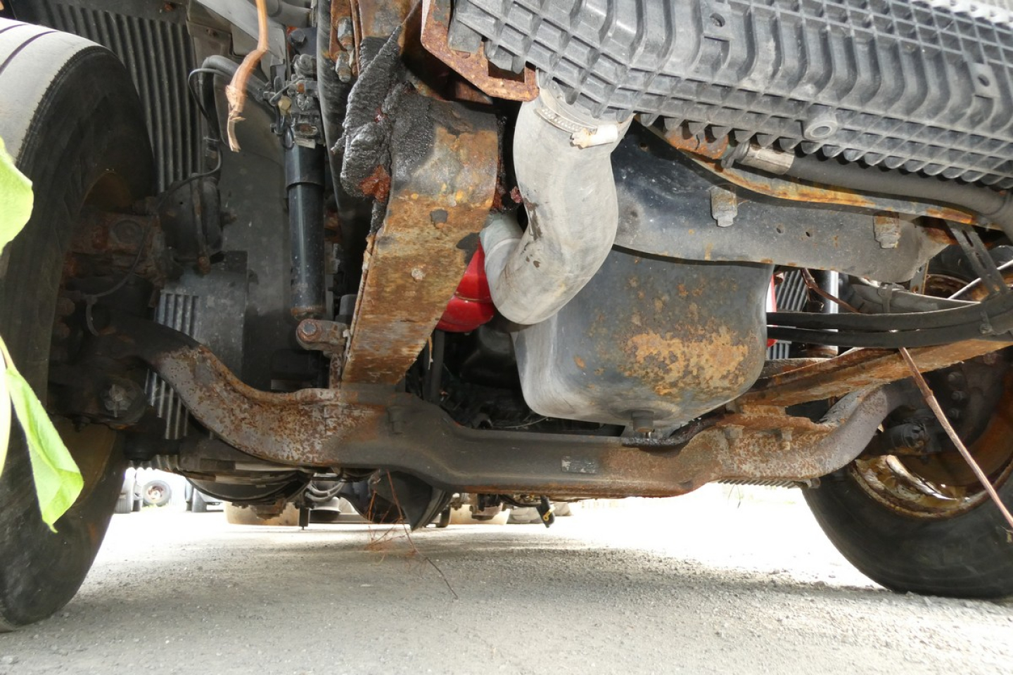 Underneath view of a 2013 Volvo VNM42T truck showing rusty suspension, frame, and components.