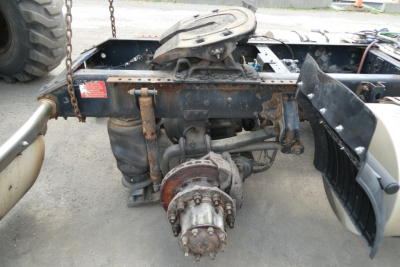 Rear view of a Volvo truck chassis showing drivetrain and differential assembly undercarriage with mounted components and chain in view.