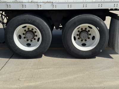 Trailer dual wheels and tires on a Wabash Duraplate trailer showing white rims and solid side rail, undercarriage visible.
