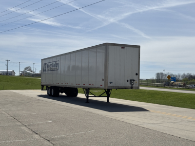 Trailer showing a Wabash Duraplate dry van trailer on a road, side view with landing gear and wheels visible, stock number 3021-2, blue sky.