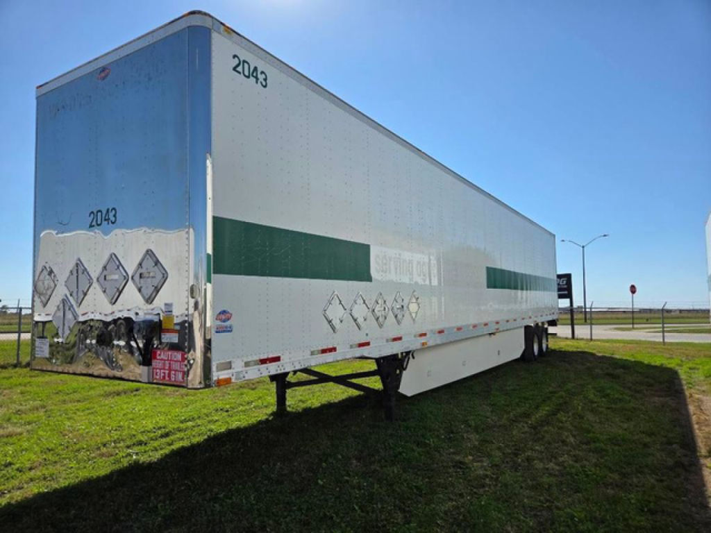 Trailer side view showing white cargo trailer with green stripe and rear doors, number 2043, parked on grass.