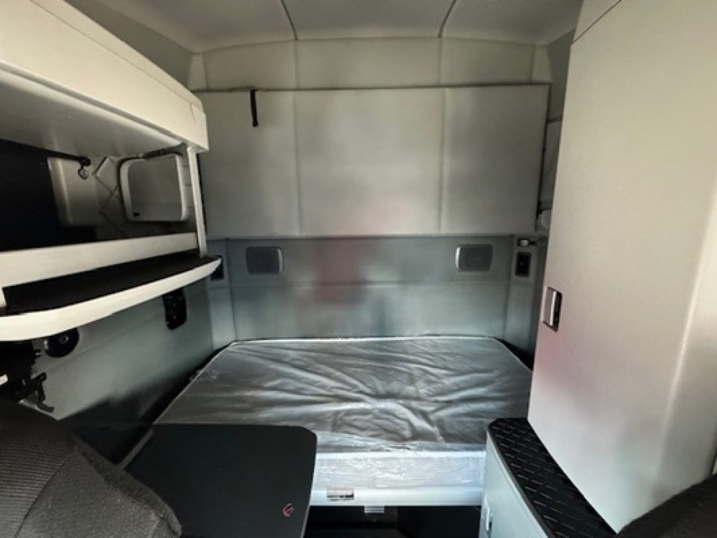 Kenworth T680 sleeper cab interior with bed in view and storage compartments.