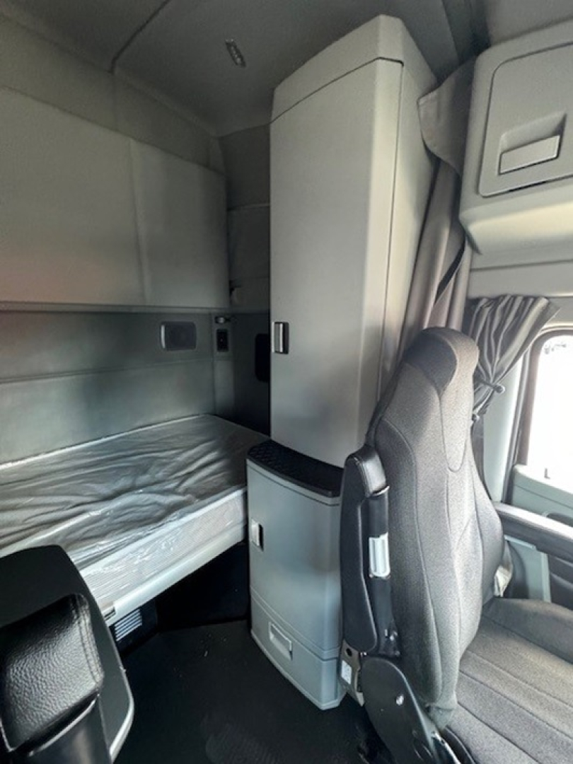 Cab interior of 2022 Kenworth T680 sleeper cab showing bunk area and overhead cabinets.