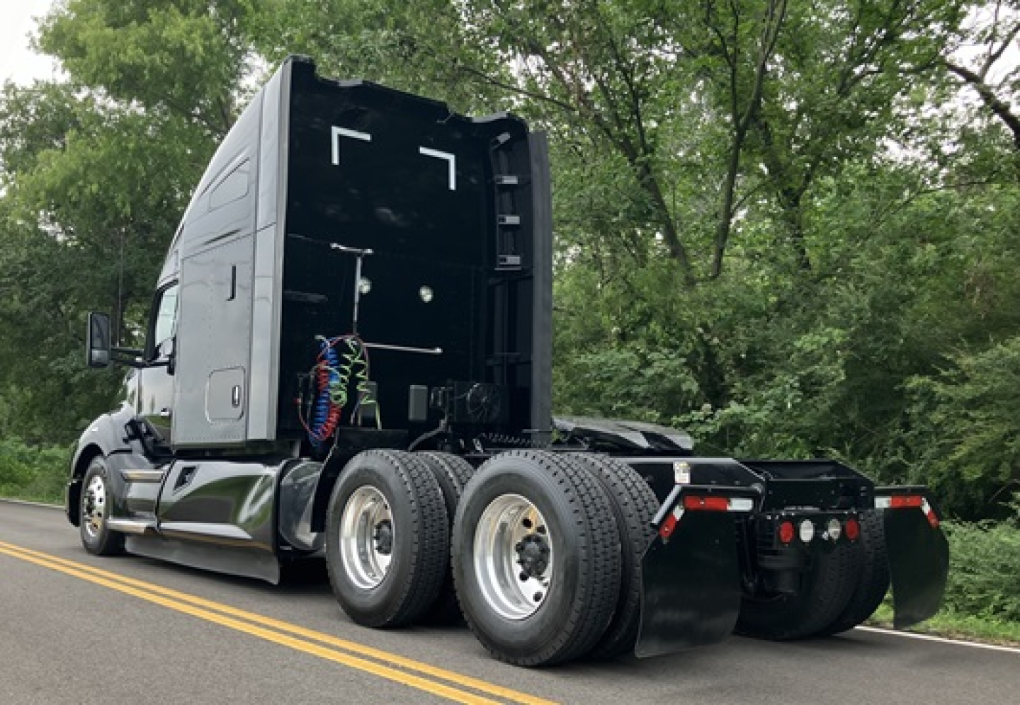 Kenworth T680 tractor conventional sleeper rear view showing dual rear axles, fifth wheel hitch, and exposed air lines.