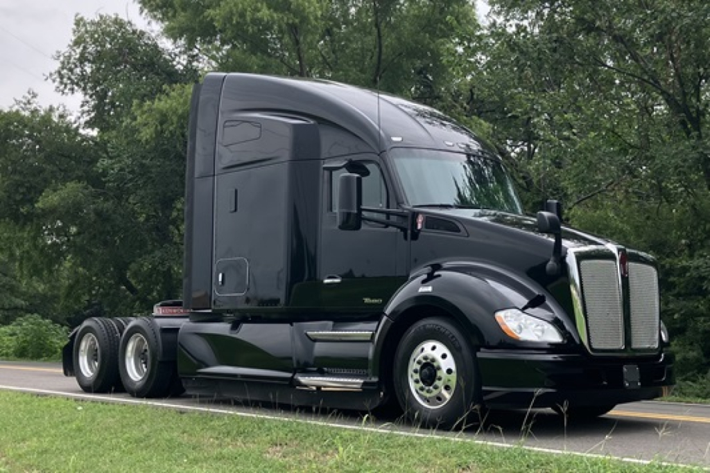 Kenworth T680 tractor in a side-view, black exterior, sleeper cab, running on highway with dual rear axles.