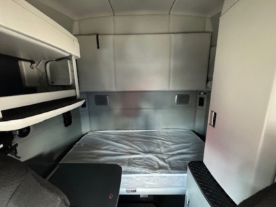 Kenworth T680 sleeper cab interior with bed in view and storage compartments.